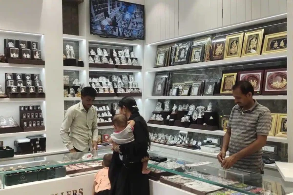 Silver price today के बीच सर्राफा बाजार की चांदी दुकान में ग्राहक और स्टाफ चांदी के आभूषण दिखाते हुए